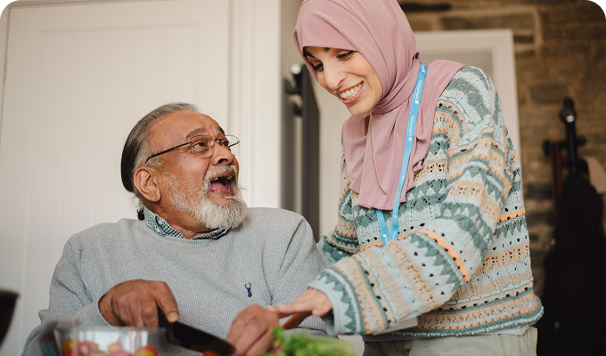 Caregiver and elderly man preparing food.