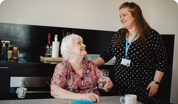 Caregiver and elderly woman smiling together.