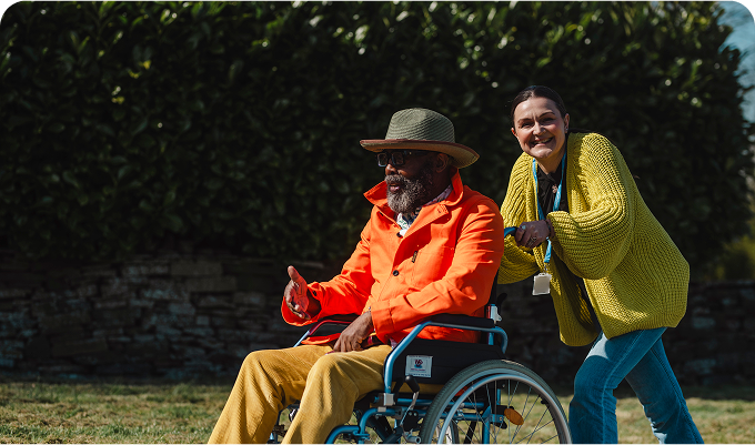 Caregiver pushing man in a wheelchair.